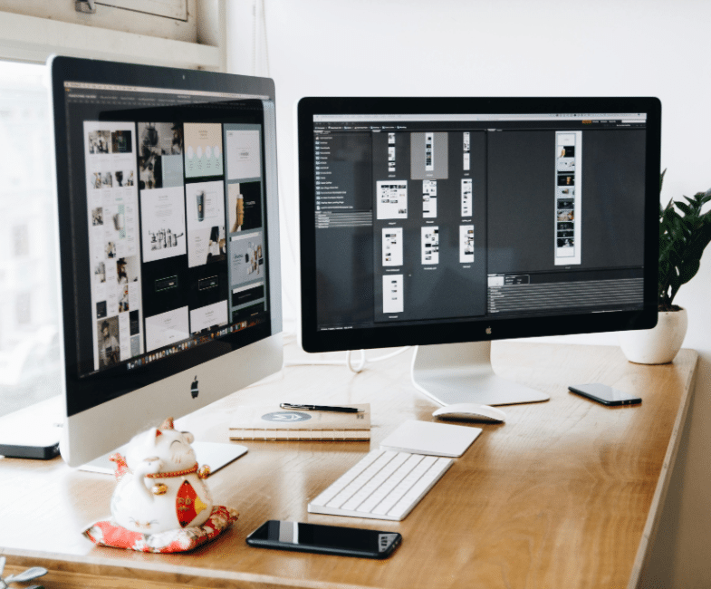 A desk with two computer screens turned on on top